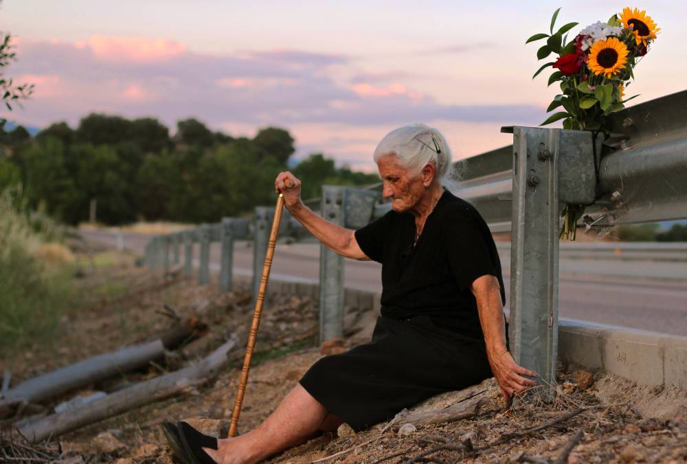El Silencio de Otros. María Martín sentada junto a la carretera bajo la que se encuentra la fosa en la que se encuentran los restos de su madre. Crédito: Almudena Carracedo